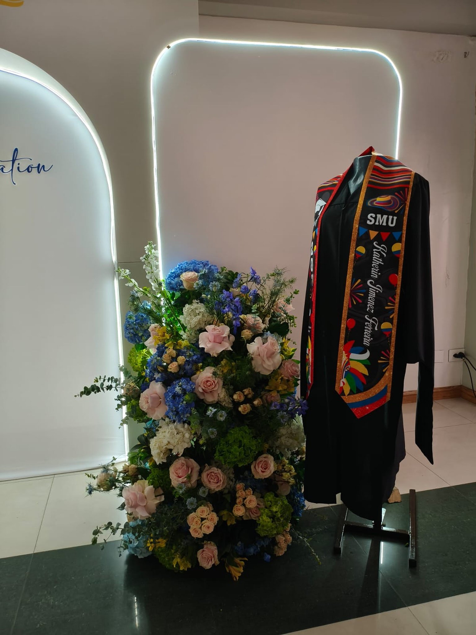 Montaje personalizado para grado en Bogotá con toga en maniquí y diseño floral en tonos azul y gris.