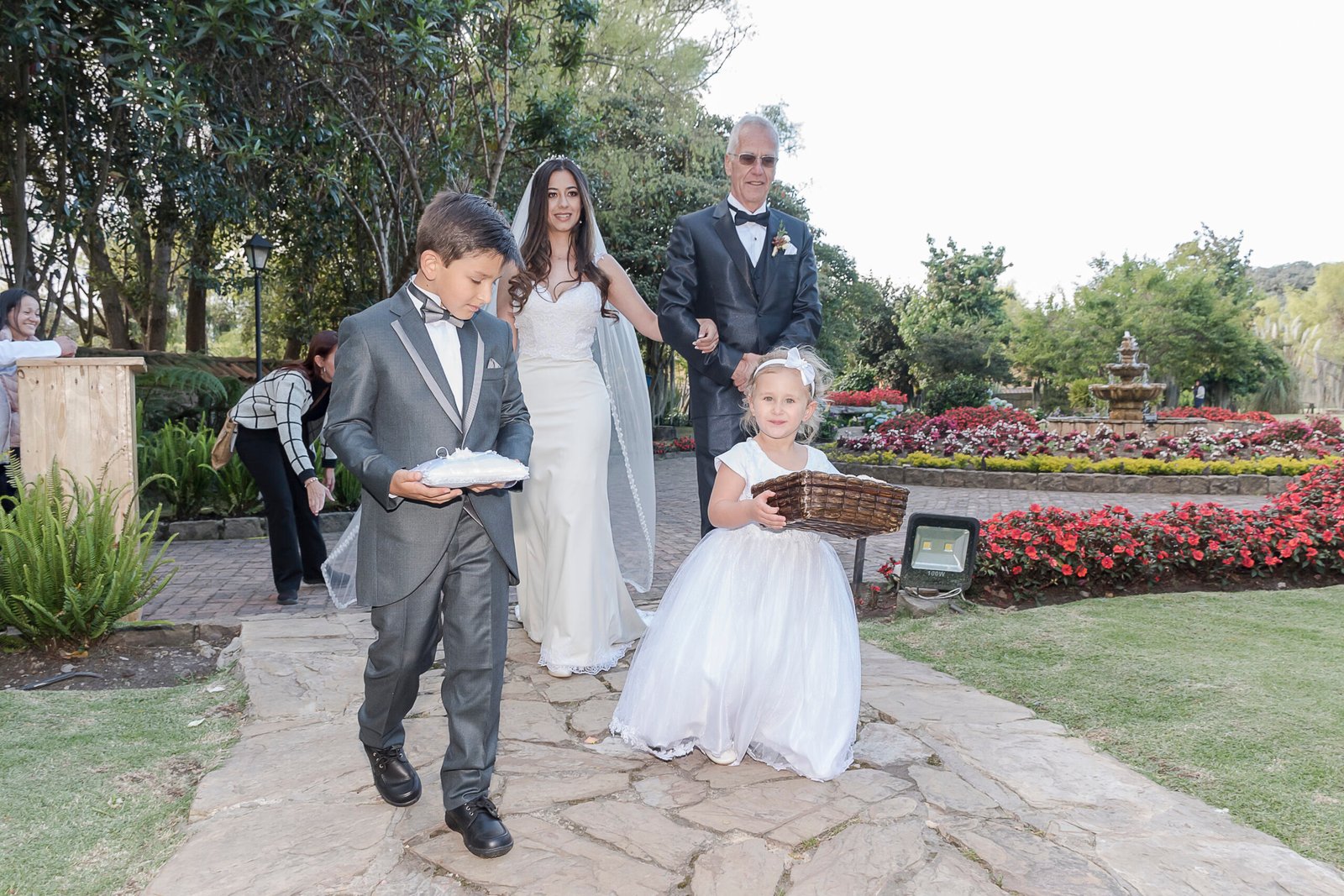 Sandra Wedding Planner acomodando el velo de una novia junto a su padre y pajes frente a una iglesia campestre en la Sabana de Bogotá.
